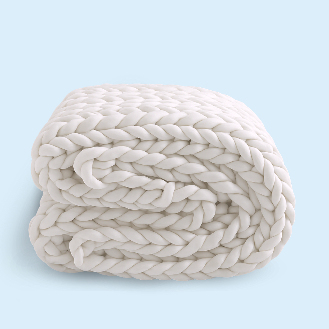 Handflätad tyngdfilt i chunky knit-stil hopvikt på en soffa